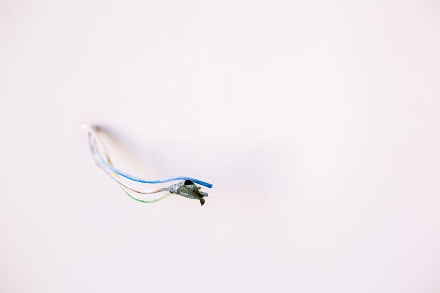 Fil électrique sortant d'un mur blanc